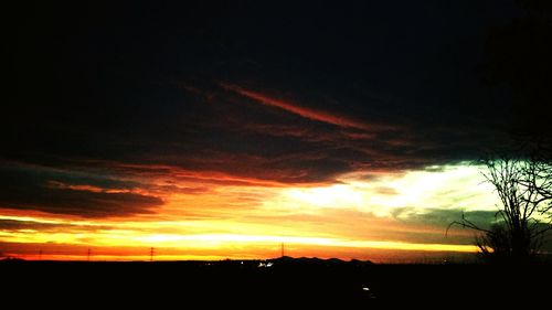 Silhouette landscape against dramatic sky during sunset