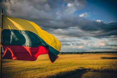 Scenic view of field and flag against sky