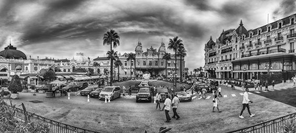 People on street by buildings in city against sky