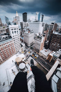 Low section of man and cityscape against sky