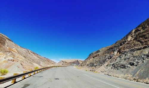 Road amidst mountains against clear blue sky