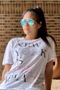 Mid adult woman wearing sunglasses standing against wall