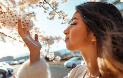 Close-up of young woman by cherry blossom tree