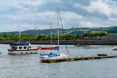 Boats moored at harbor against sky