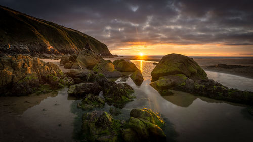 Scenic view of sea against cloudy sky during sunset