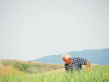 Man relaxing on field against clear sky