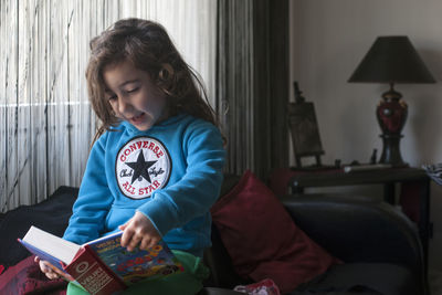 Girl sitting on book at home
