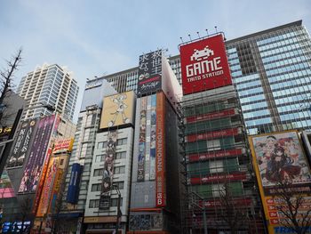 Low angle view of taito game station against sky in city