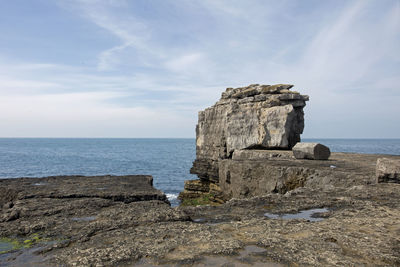 Rock formation on beach against sky