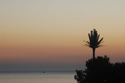 Silhouette tree by sea against sky during sunset