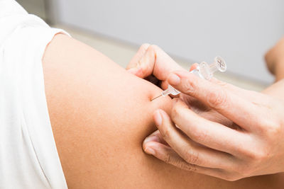 Cropped hand of female doctor vaccinating male patient in clinic