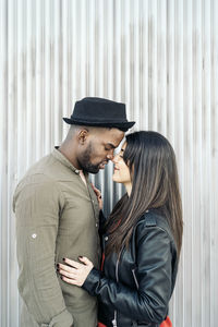 Side view of young couple standing against wall