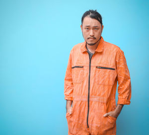 Portrait of man standing against blue background