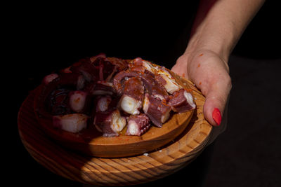 Close-up of hand holding ice cream over black background