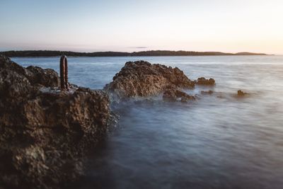 Rocks on beach against sky during sunset