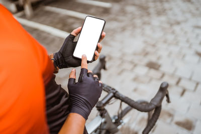 Midsection of woman using mobile phone on bicycle