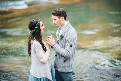 Young couple standing by lake