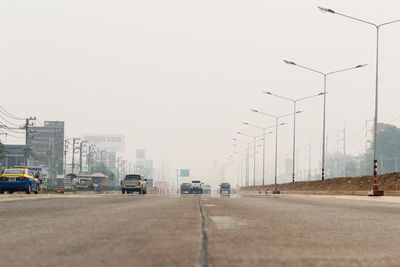 Cars on road against sky in city