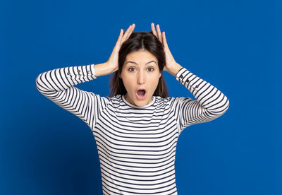 Portrait of young woman against blue background