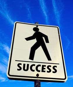 Low angle view of success sign against blue sky