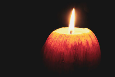 Close-up of lit candle against black background