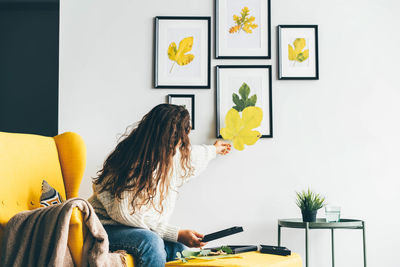 Rear view of woman using digital tablet while sitting on table