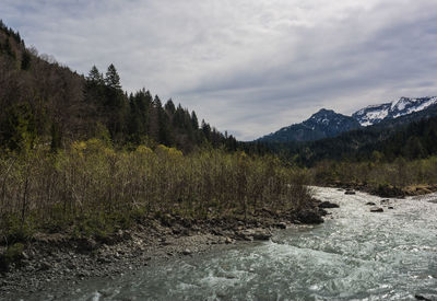 Scenic view of river by mountains against sky
