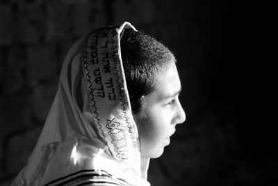 Side view of young man wearing headwear against wall
