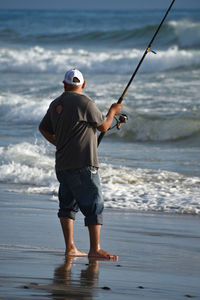 Rear view of man fishing on beach
