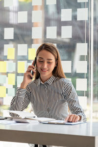 Portrait of young woman using mobile phone in office