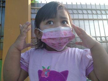 Portrait of cute girl holding pink mask