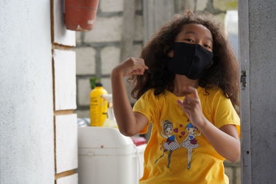 Portrait of woman standing against yellow wall