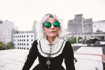 Portrait of woman wearing sunglasses sitting on rooftop