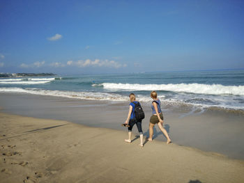 Two people walking on calm beach