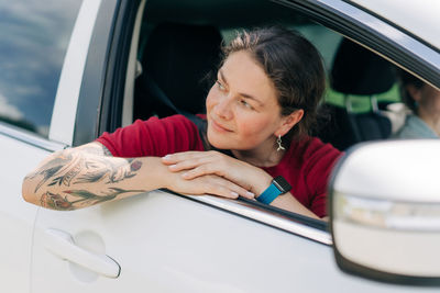 Portrait of young woman using mobile phone while sitting in car