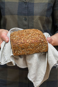 Mature senior woman holding freshly baked loaf of homemade rye bread in her hands