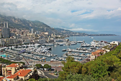 High angle view of cityscape by sea against cloudy sky