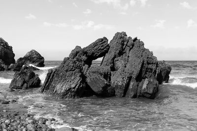 Rock formation on beach against sky