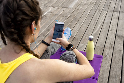 Above view of young woman sitting on mat using mobile,listening music