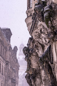 Low angle view of statue amidst buildings in city