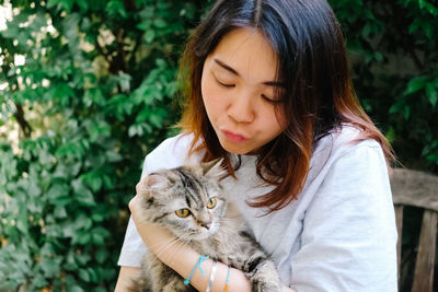 Woman with cat sitting against plants