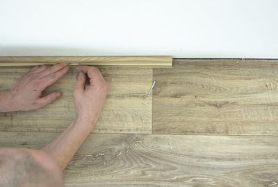 High angle view of man hand on hardwood floor at home