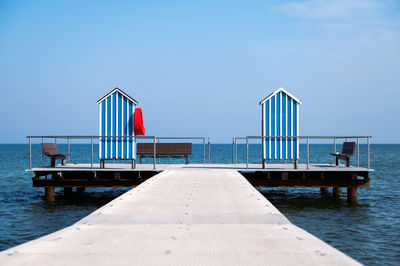 Pier on sea against clear blue sky