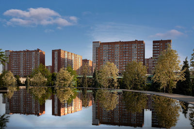 Reflection of trees and buildings in lake against sky