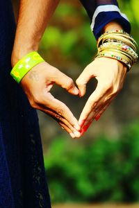 Cropped image of couple making heart shape with hand