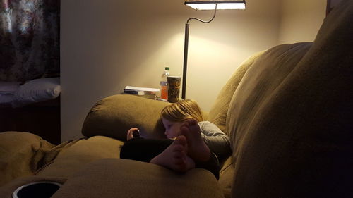 Rear view of child relaxing on bed