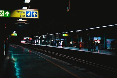 People on illuminated railroad station platform at night