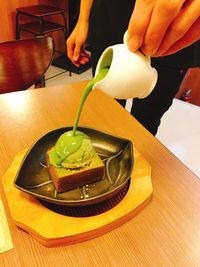 Midsection of woman holding ice cream in bowl on table