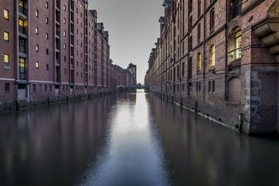 Canal in city against sky