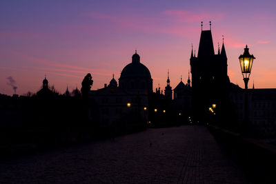 Silhouette of towers of old town in prague, view from illuminated charles bridge during sunrise